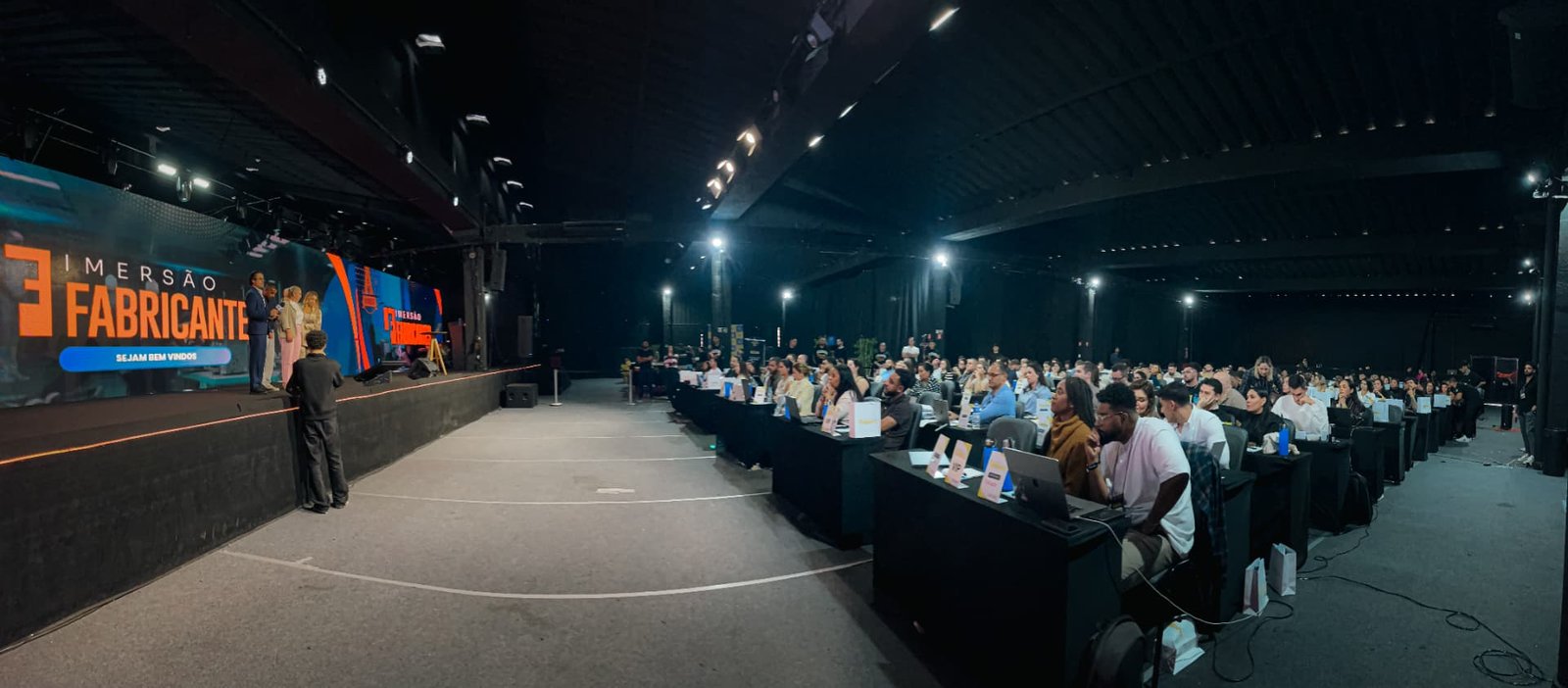 Palco e participantes vistos pela lateral da plenária