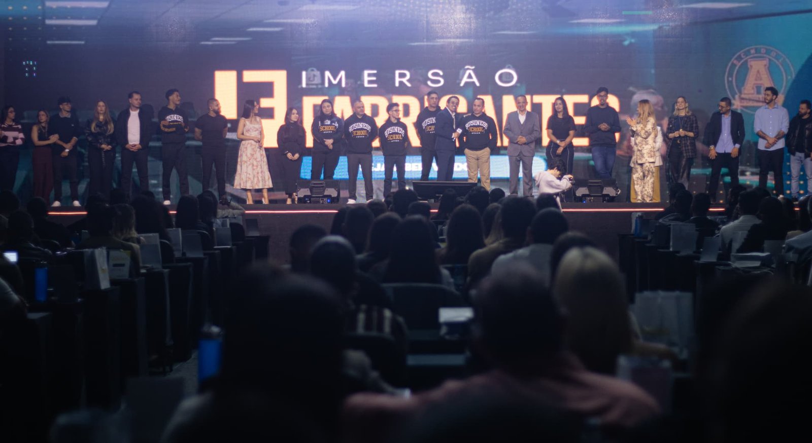 Público acompanhando participantes reunidos no palco
